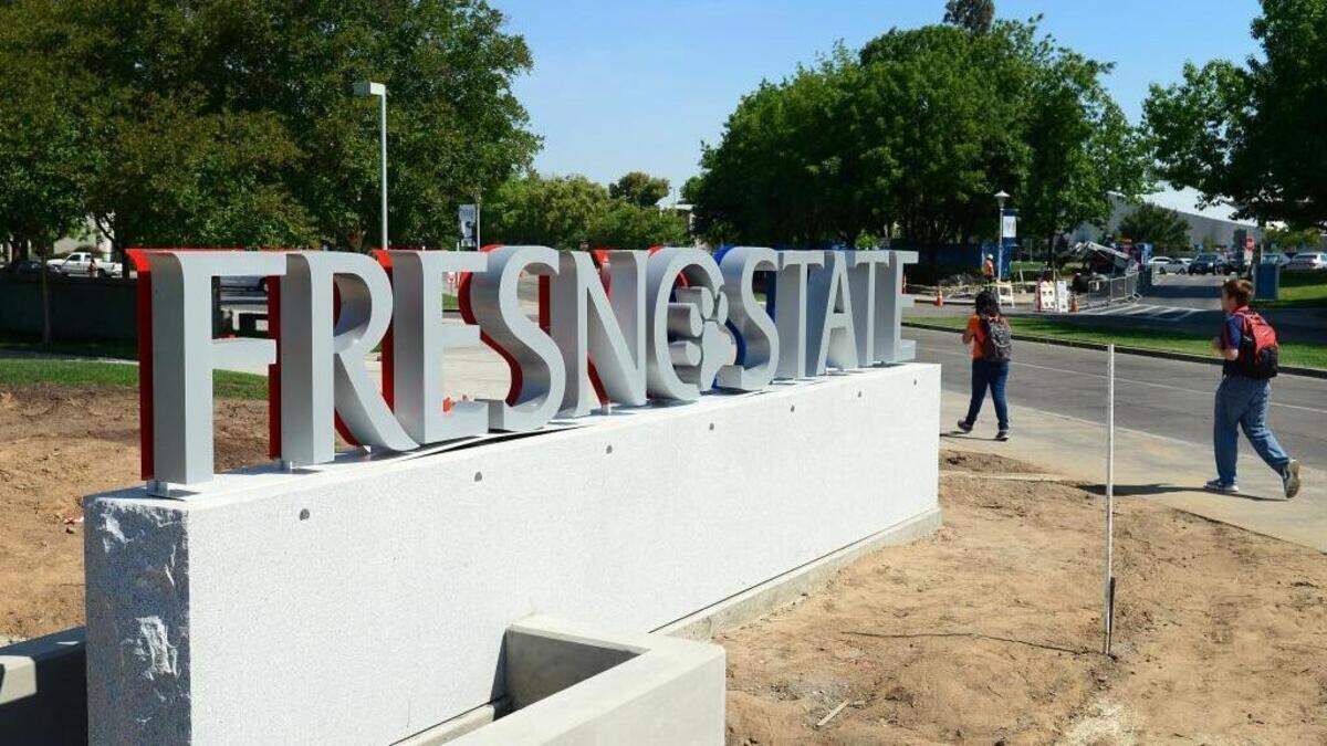 Students walk by a new gateway sign at the entrance to Fresno State at Maple and Shaw avenues.